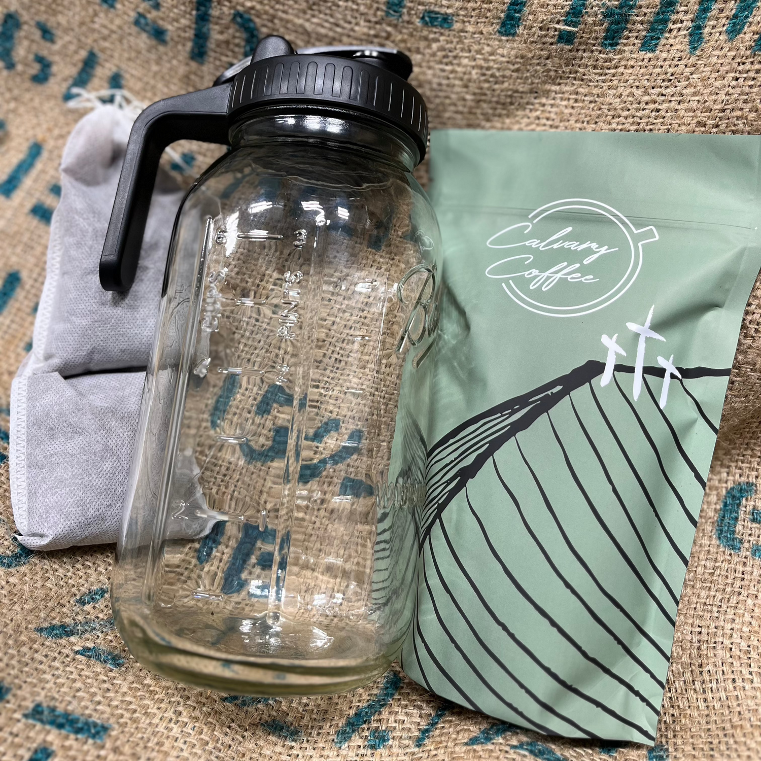 Glass jar, pour lid, two steeping coffee bags, and a Calvary Coffee bag with four steeping coffee bags.